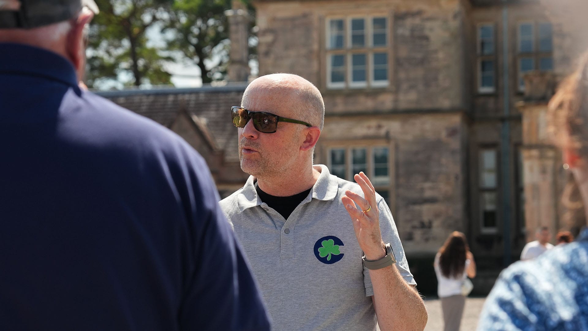 Mark at Muckross Tour guide explains to a small group of people with an old structure is visible in the background